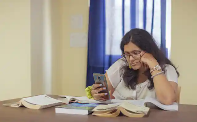 मोबाईलवर ऑनलाइन मदत पाहणारी महिला