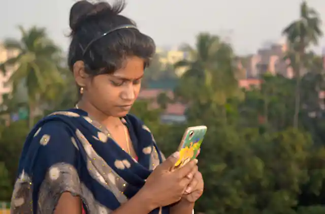 रेशन कार्ड सेवेसाठी मोबाईल वापरणारी महिला