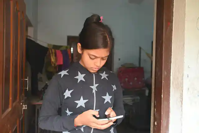 मोबाईलवर योजना KYC पाहणारी महिला